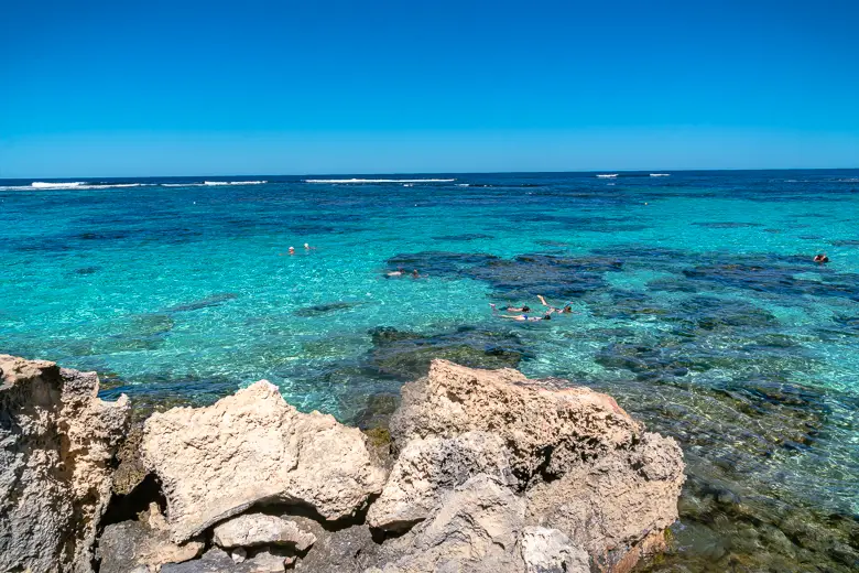 The incredible light blue water at Little Salmon Bay where people are snorkelling in this photo in Rottnest Island in Perth